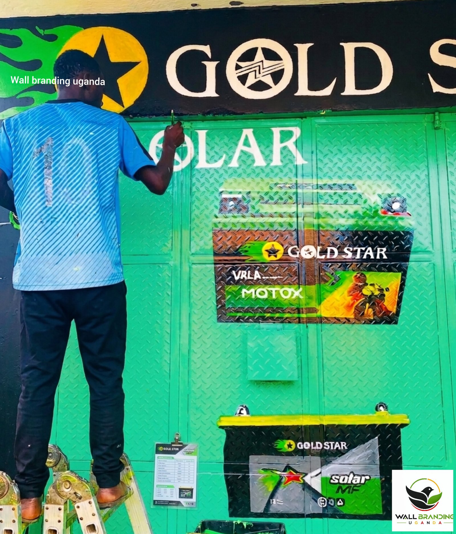 Painter applying custom door wall branding and artwork for Goldstar Solar and Batteries in Uganda